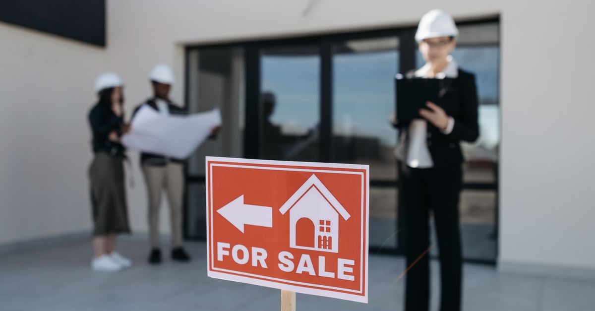 Three real estate professionals inspecting a property for sale with a focus on the business aspect.