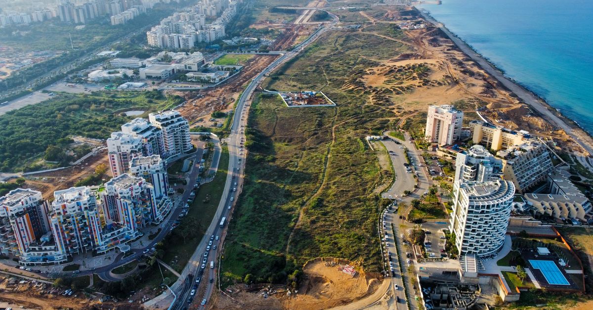Breathtaking aerial view of urban development along a picturesque coastline, showcasing city and natural beauty.
